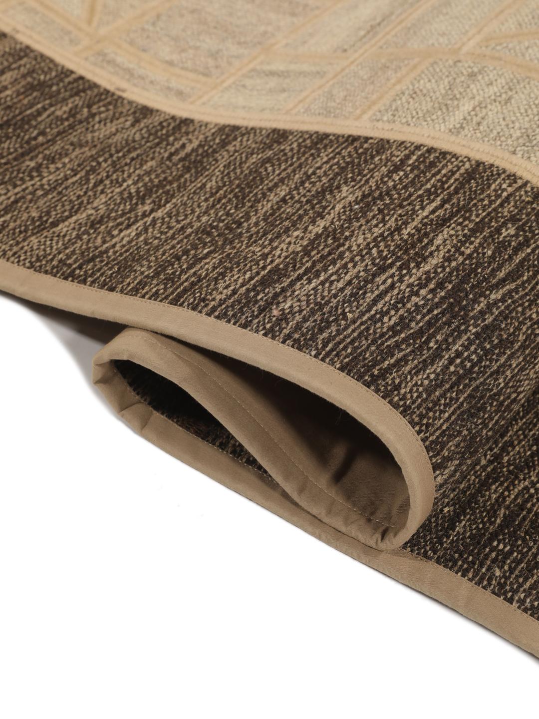 Un tapis patchwork rectangulaire avec des motifs géométriques en beige et marron, tissé à la main au Moyen-Orient.