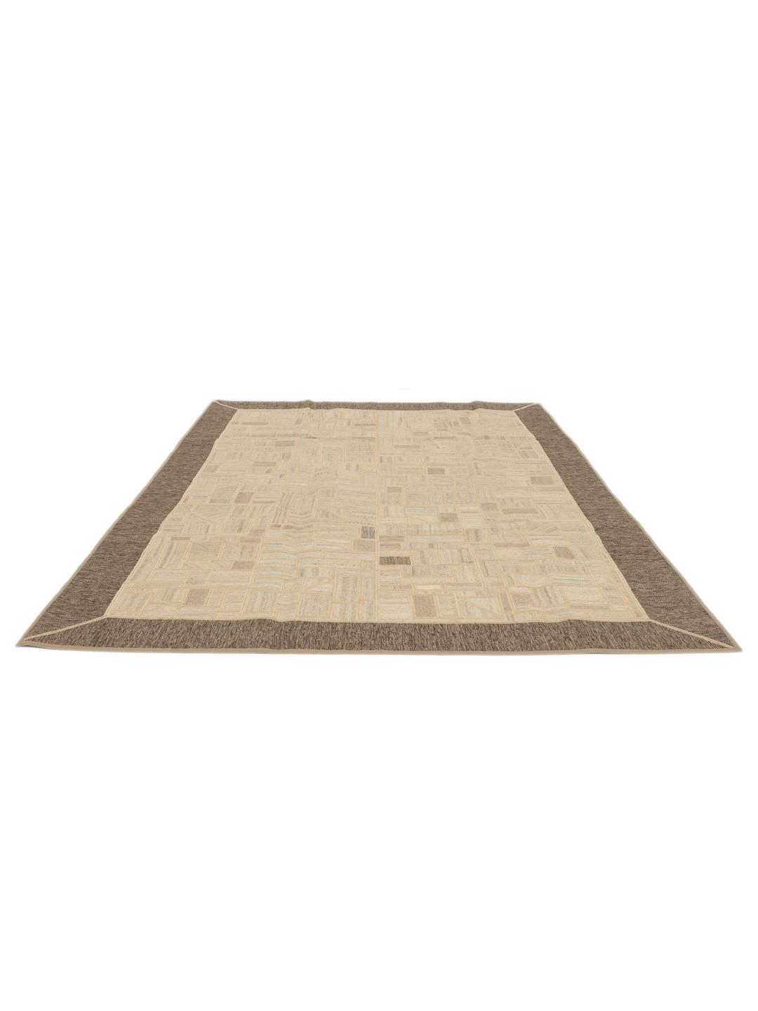 Een uniek rechthoekig patchwork tapijt met geometrische patronen in beige- en bruintinten.