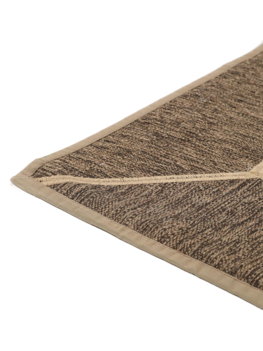 Een uniek rechthoekig patchwork tapijt met geometrische patronen in beige- en bruintinten.