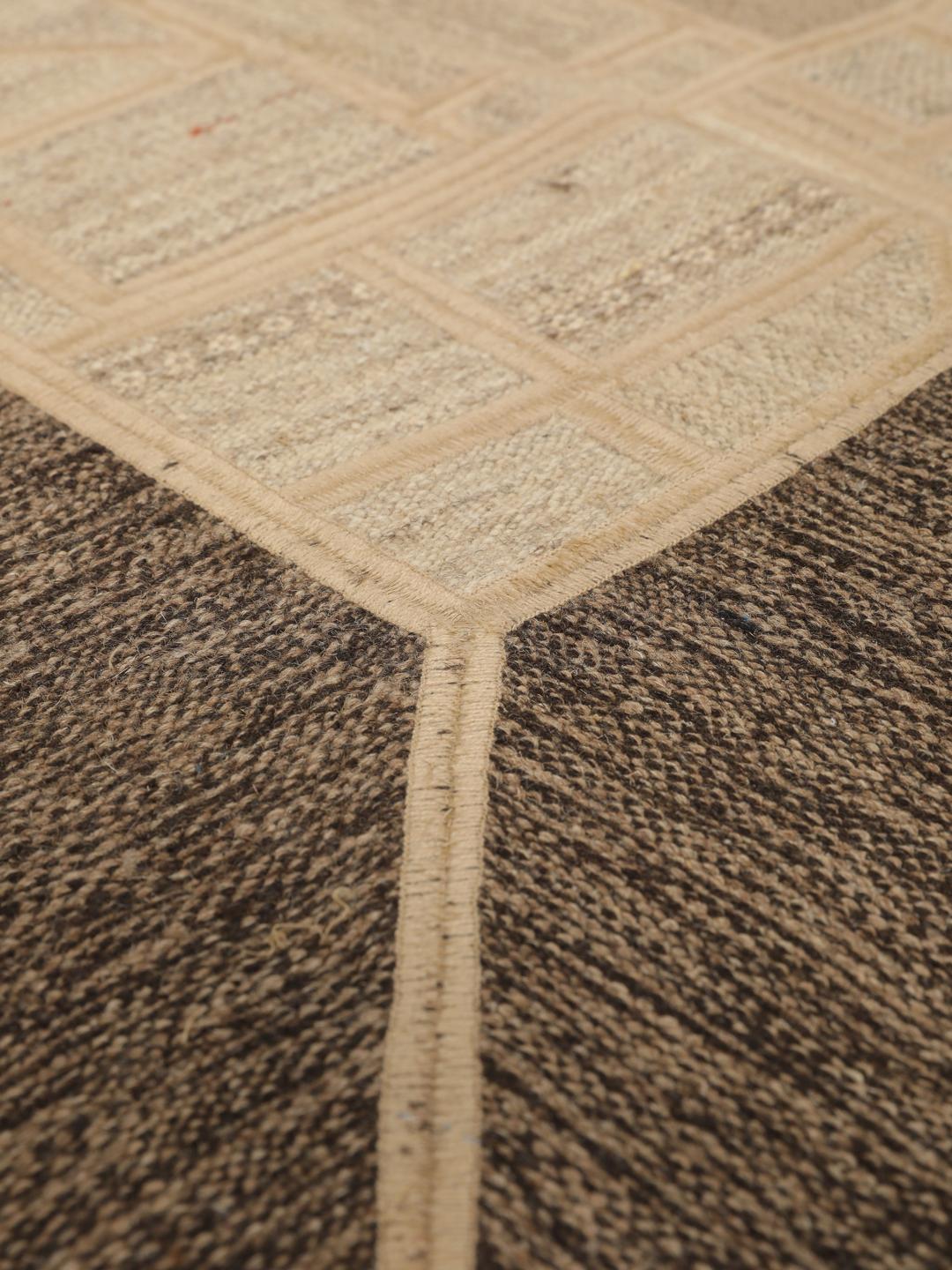 Een uniek rechthoekig patchwork tapijt met geometrische patronen in beige- en bruintinten.
