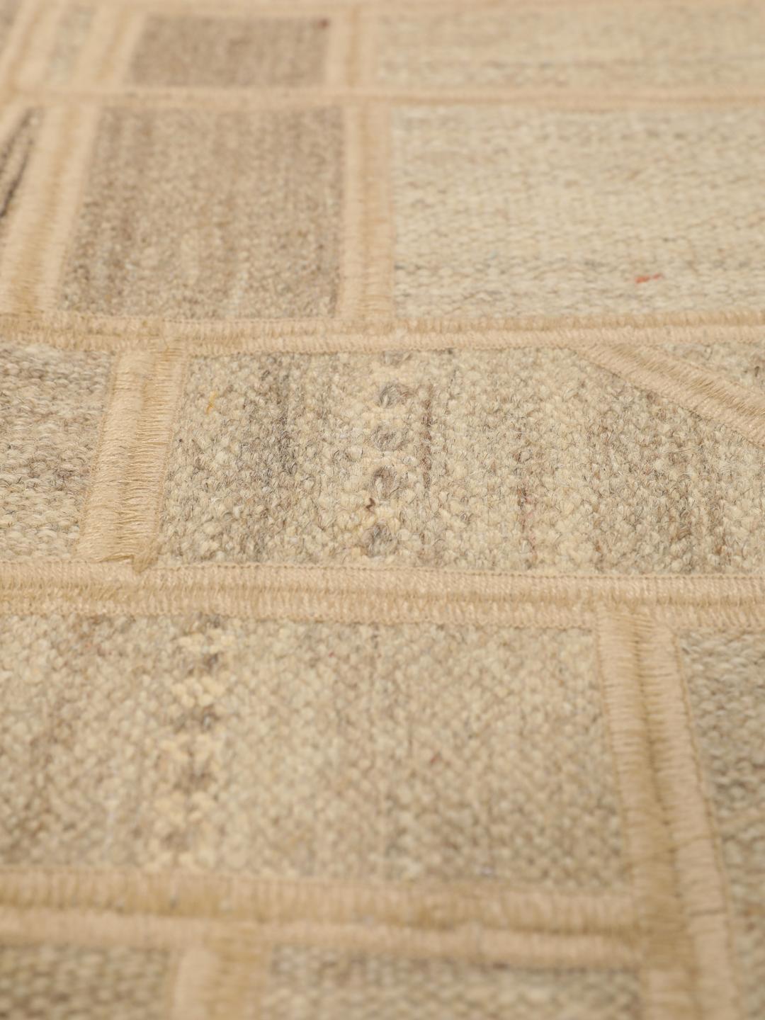 Een uniek rechthoekig patchwork tapijt met geometrische patronen in beige- en bruintinten.