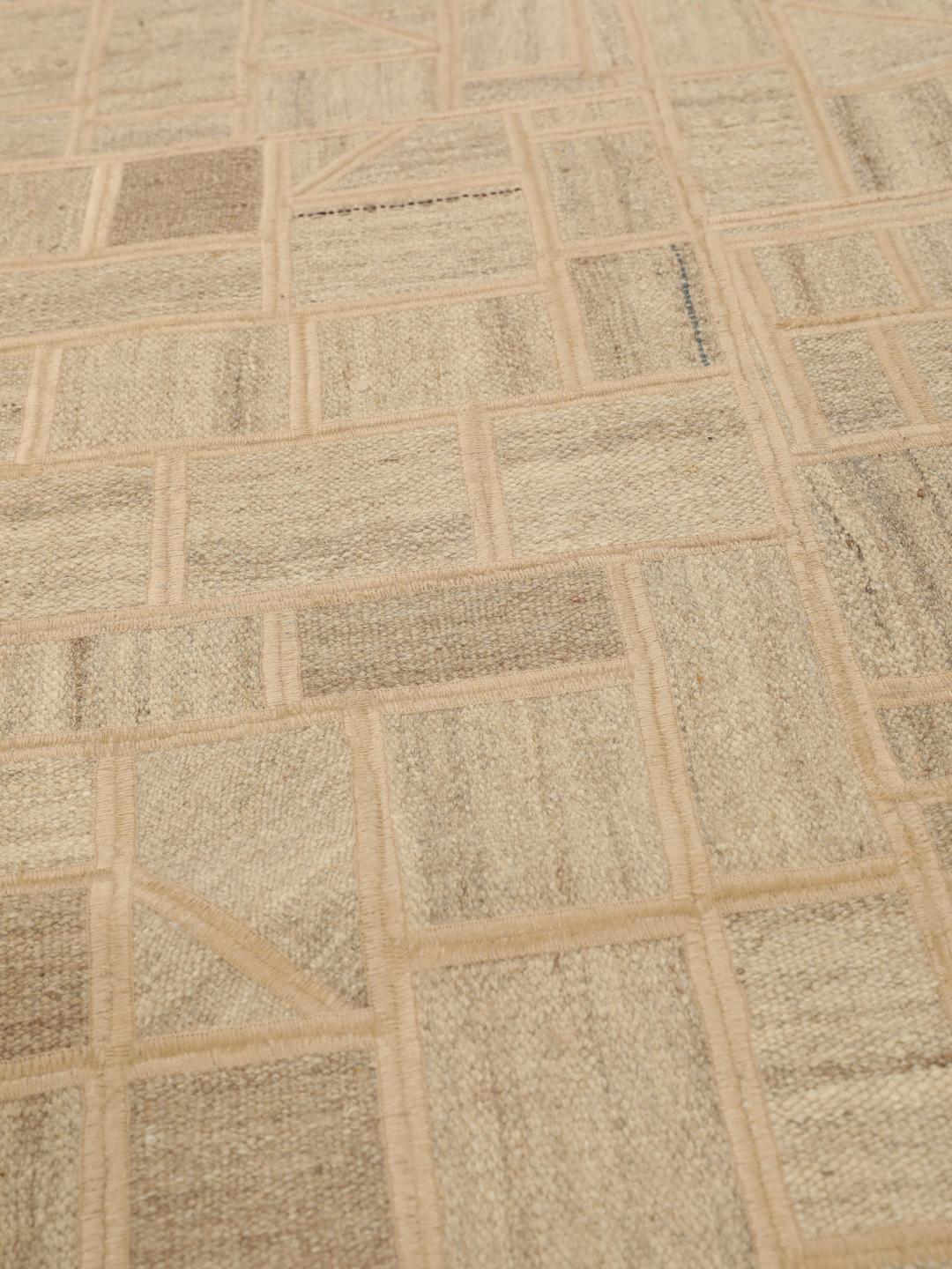 Een uniek rechthoekig patchwork tapijt met geometrische patronen in beige- en bruintinten.