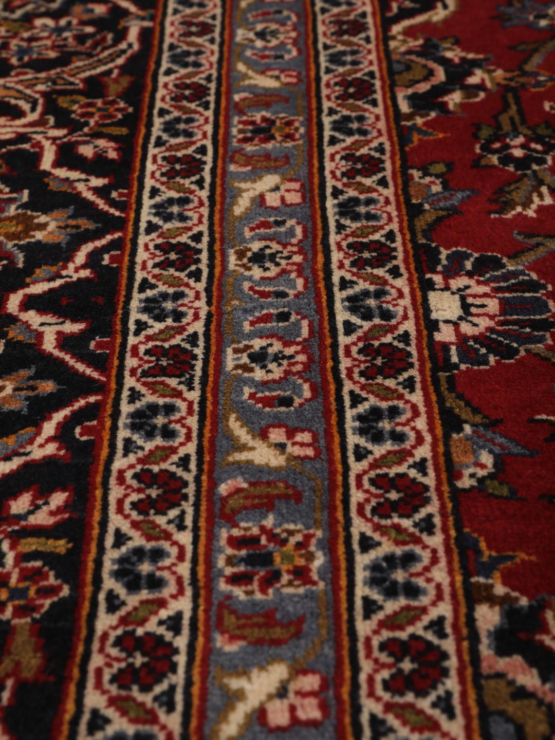 Handgeknoopt Keshan-tapijt uit het Midden-Oosten met een donkerrood veld en bloemmotieven.
