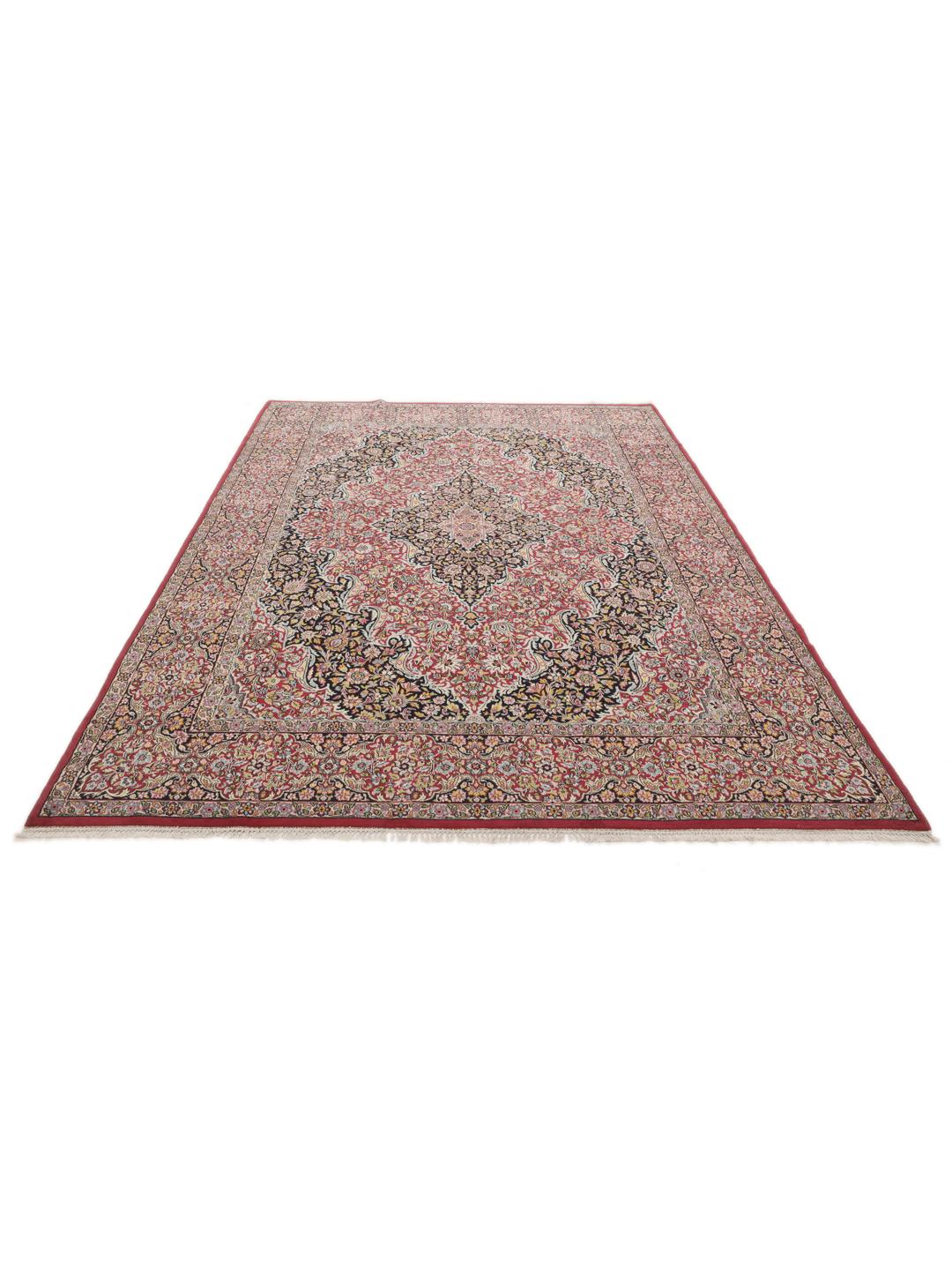 A hand-knotted Kerman rug with a floral medallion design in red and dark tones.