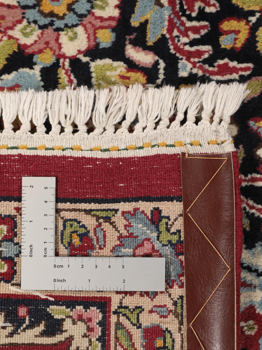 A hand-knotted Kerman rug with a floral medallion design in red and dark tones.