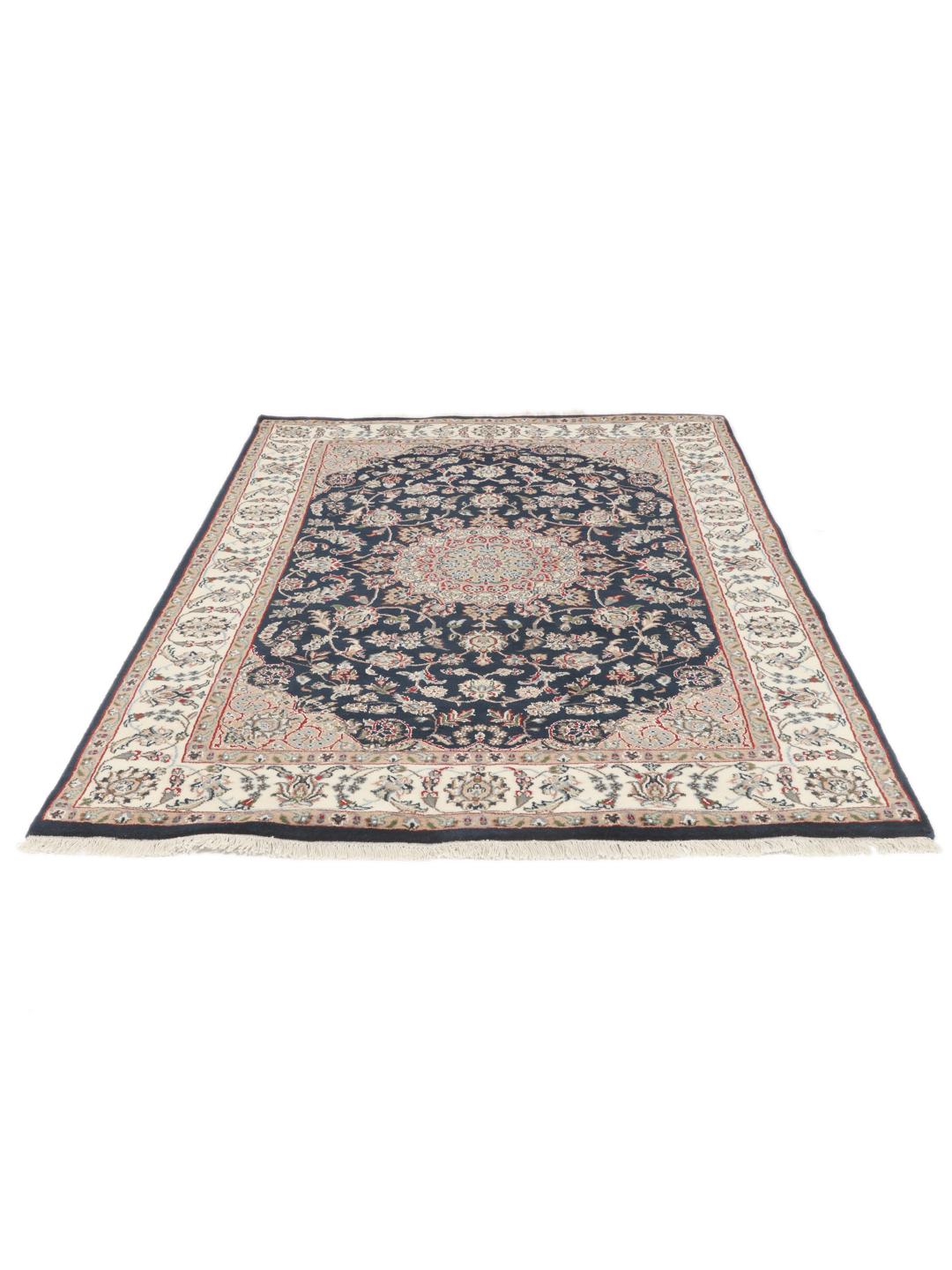 Un tapis rectangulaire Nain Indo présentant un champ bleu foncé avec un médaillon floral central et des bordures complexes, noué à la main en Inde.