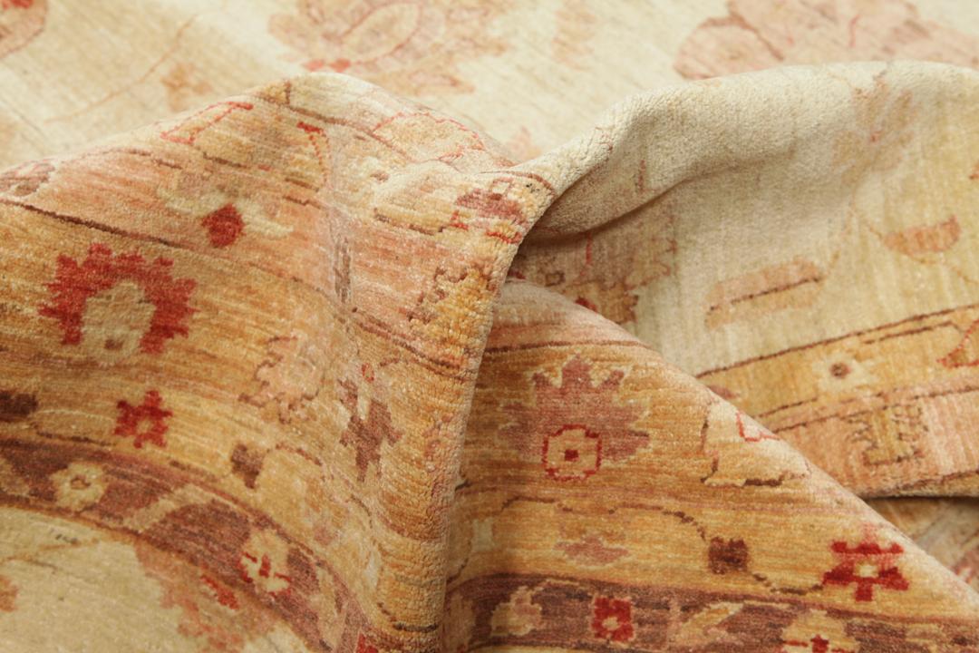 A large, hand-knotted Ziegler rug from Pakistan featuring a neutral beige and soft red floral pattern.