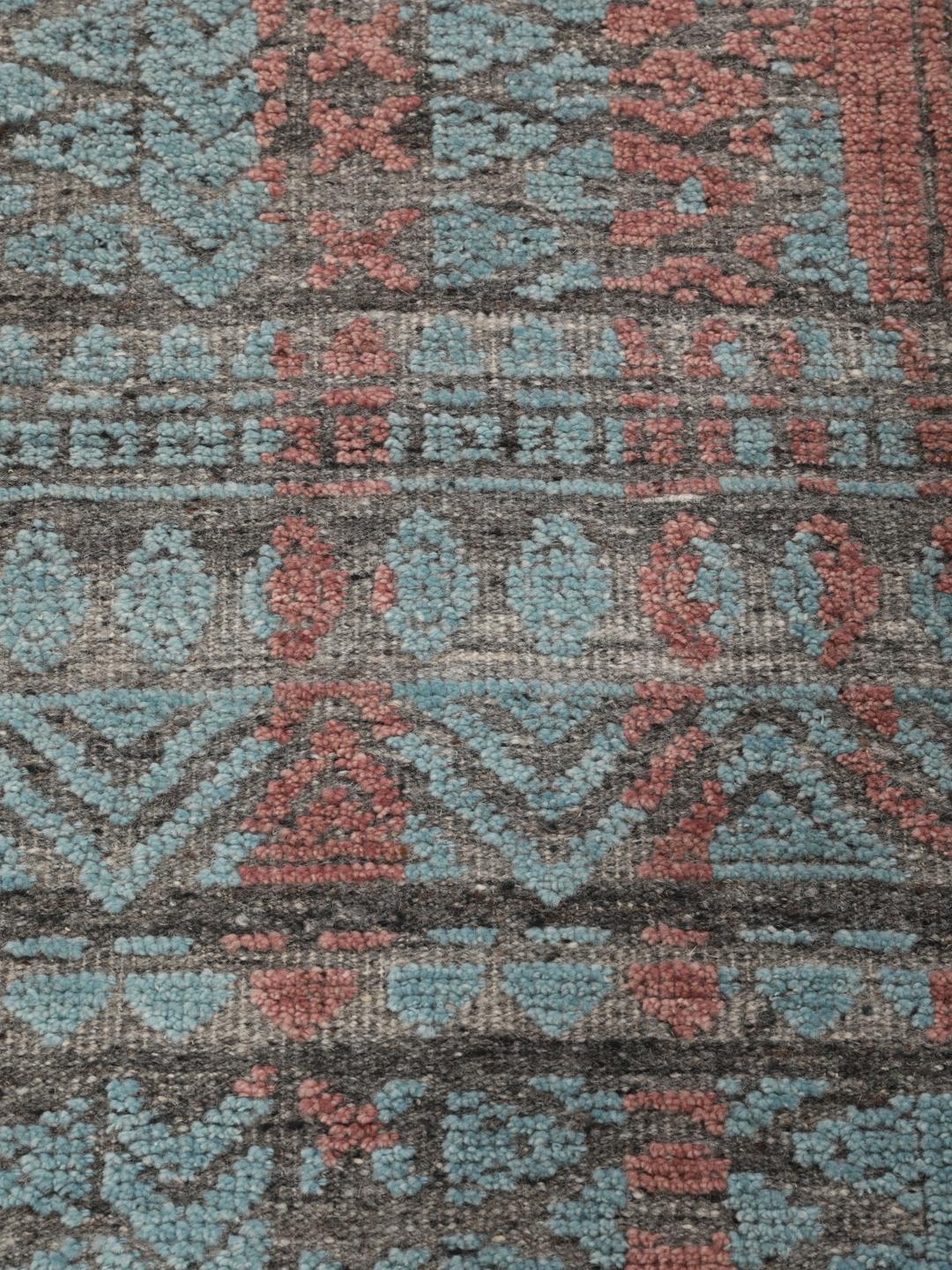 Een modern handgeknoopt Indiaas tapijt met een meerkleurig ontwerp in blauwgroene en aardse tinten.