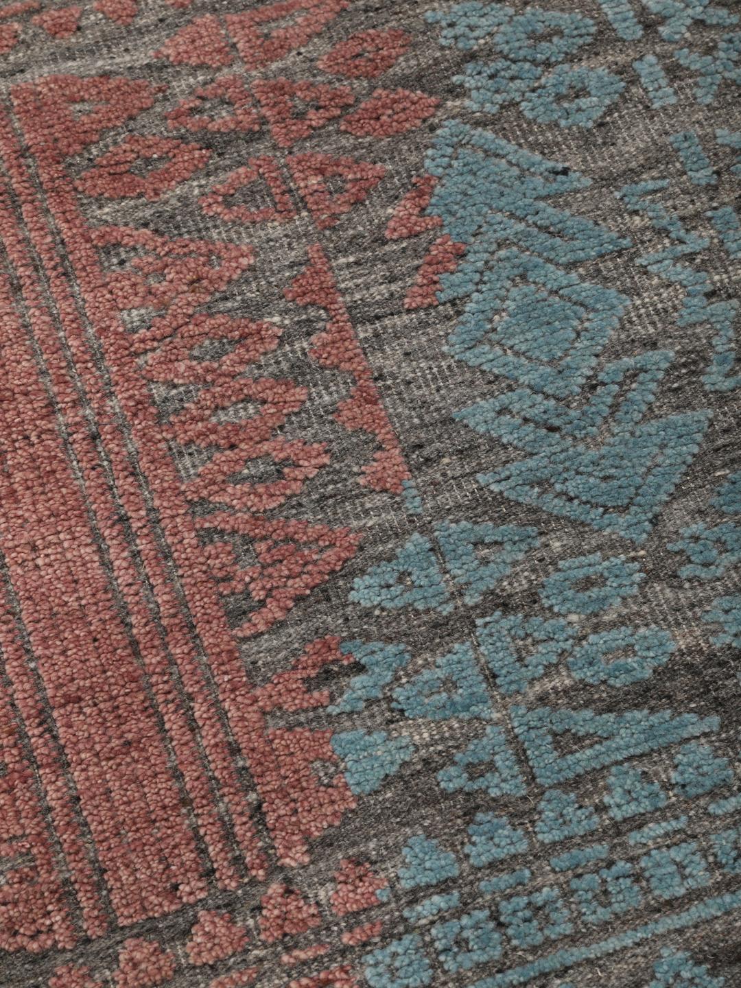 Een modern handgeknoopt Indiaas tapijt met een meerkleurig ontwerp in blauwgroene en aardse tinten.
