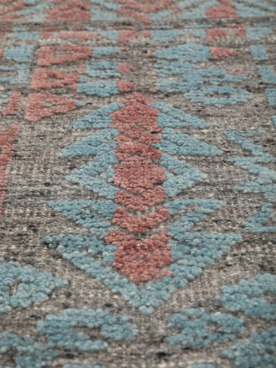 Een modern handgeknoopt Indiaas tapijt met een meerkleurig ontwerp in blauwgroene en aardse tinten.