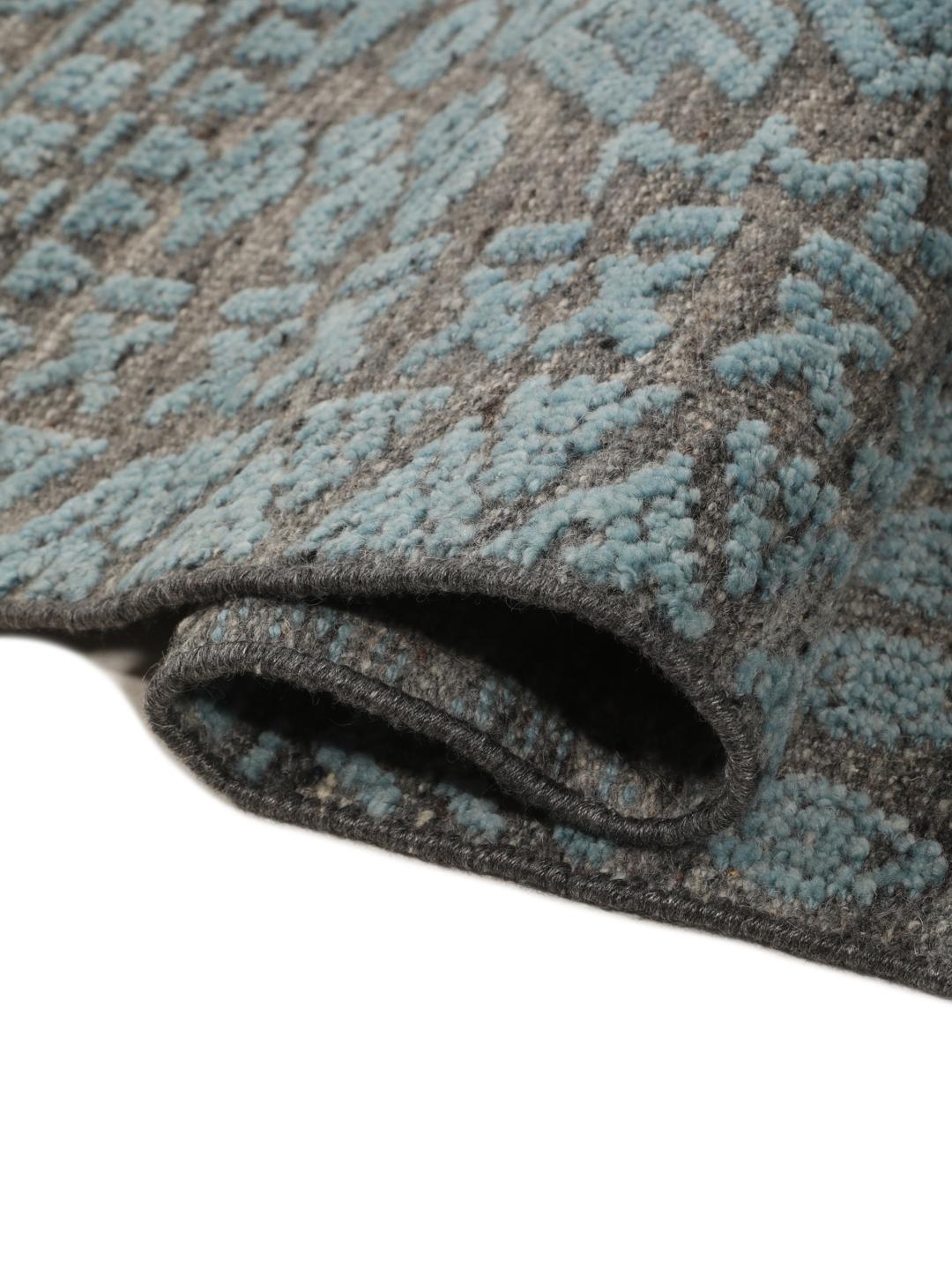 Een modern handgeknoopt Indiaas tapijt met een meerkleurig ontwerp in blauwgroene en aardse tinten.