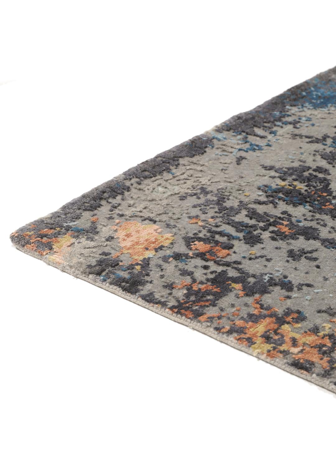 Een modern handgeknoopt tapijt uit India met een abstract ontwerp in grijze, blauwe en oranje tinten.