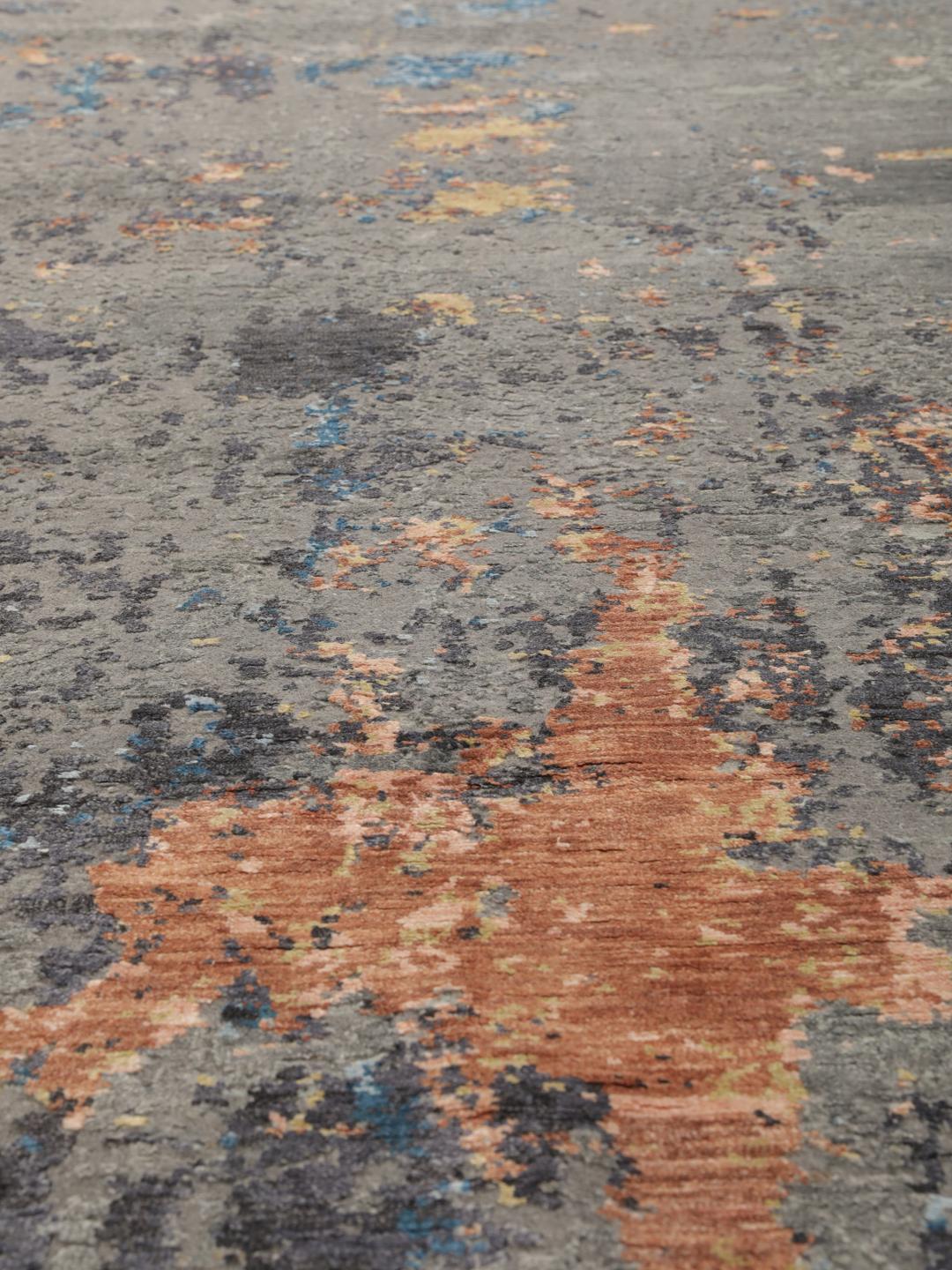 Een modern handgeknoopt tapijt uit India met een abstract ontwerp in grijze, blauwe en oranje tinten.