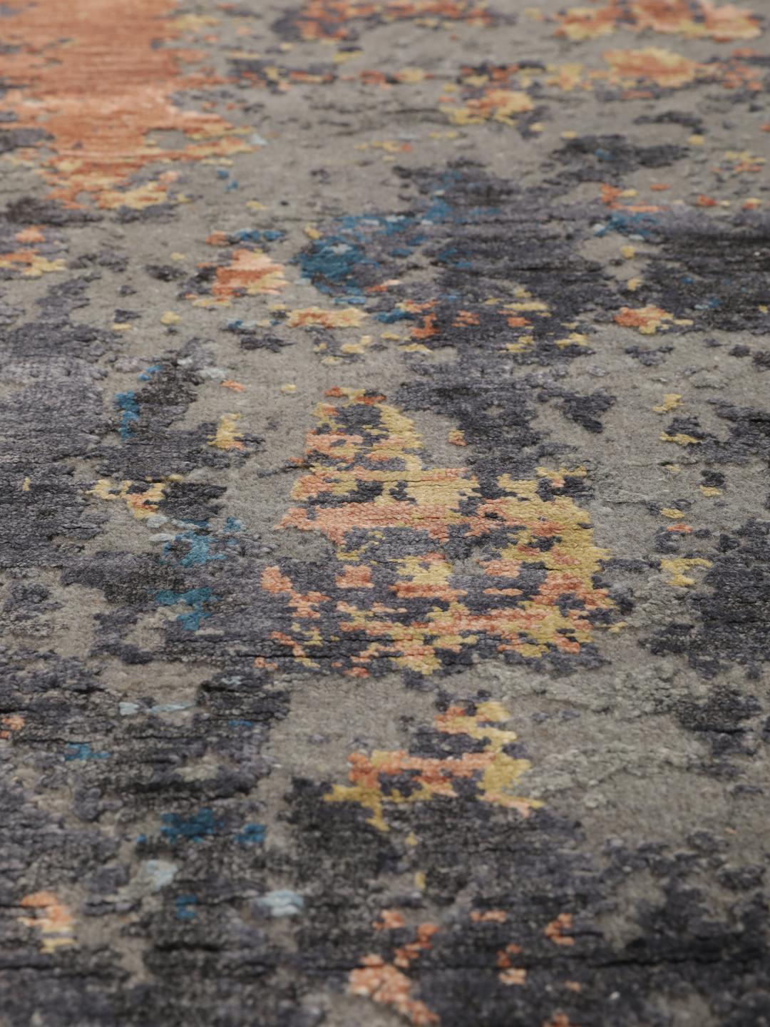 Een modern handgeknoopt tapijt uit India met een abstract ontwerp in grijze, blauwe en oranje tinten.