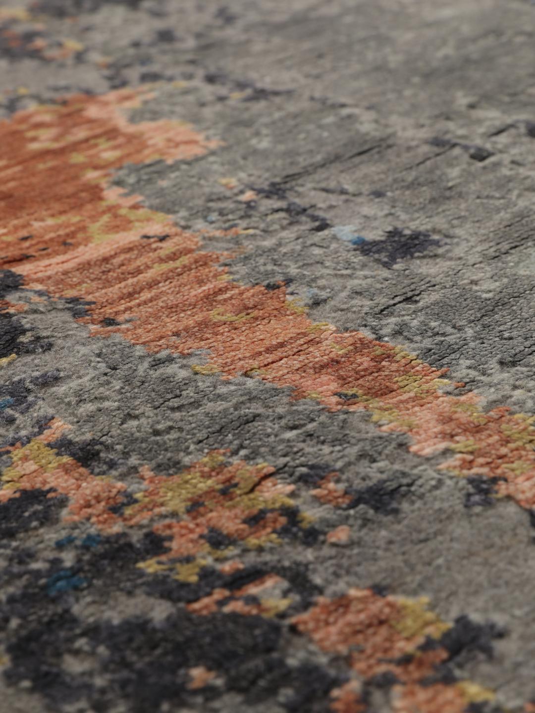 Een modern handgeknoopt tapijt uit India met een abstract ontwerp in grijze, blauwe en oranje tinten.