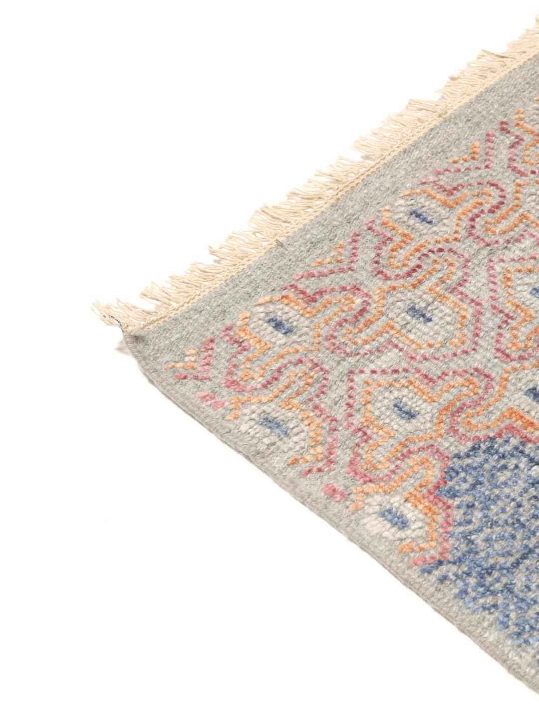 Modern handgeknoopt tapijt uit India met geometrische patronen in blauwe, roze en beige tinten.