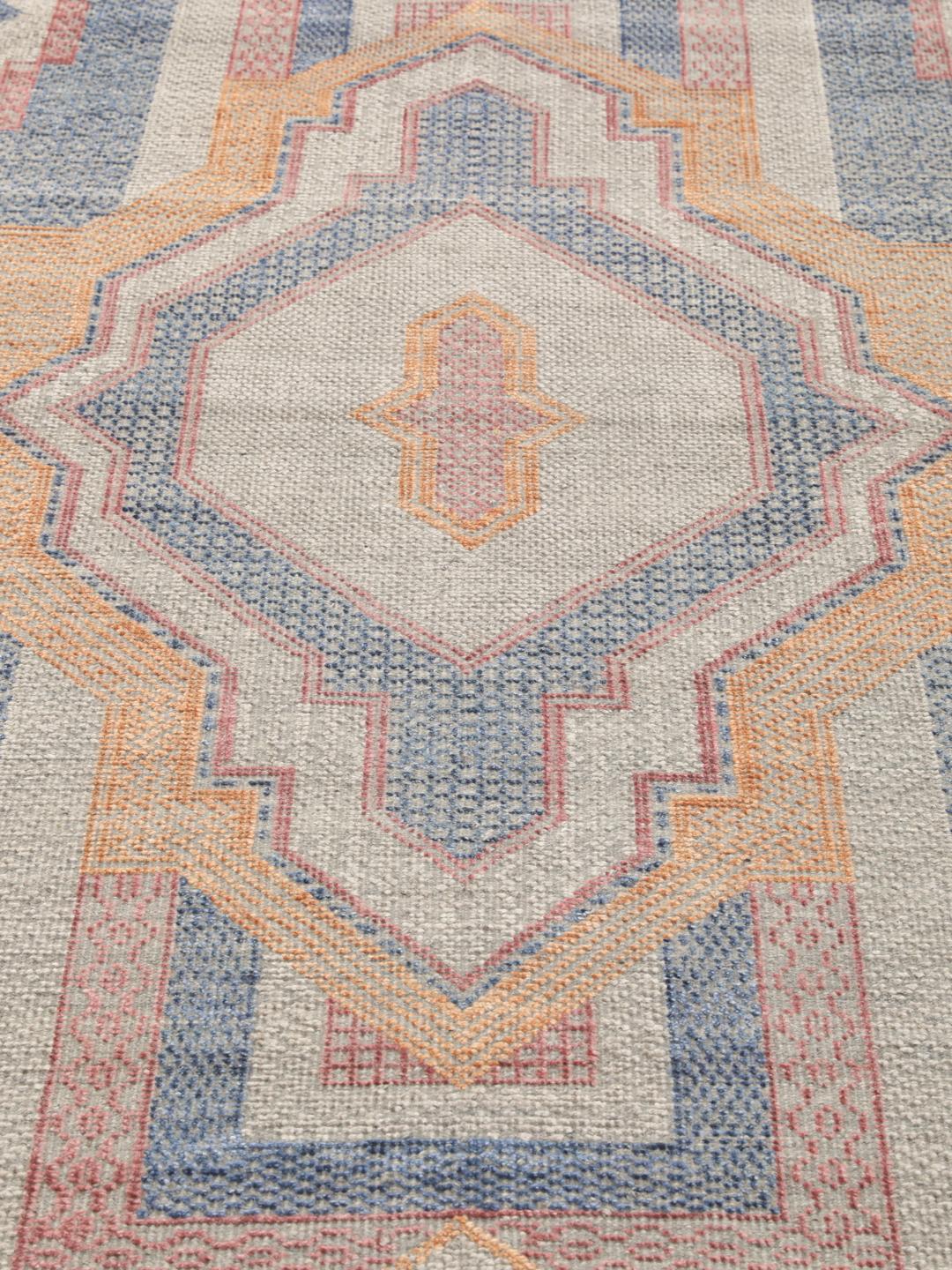 Modern handgeknoopt tapijt uit India met geometrische patronen in blauwe, roze en beige tinten.