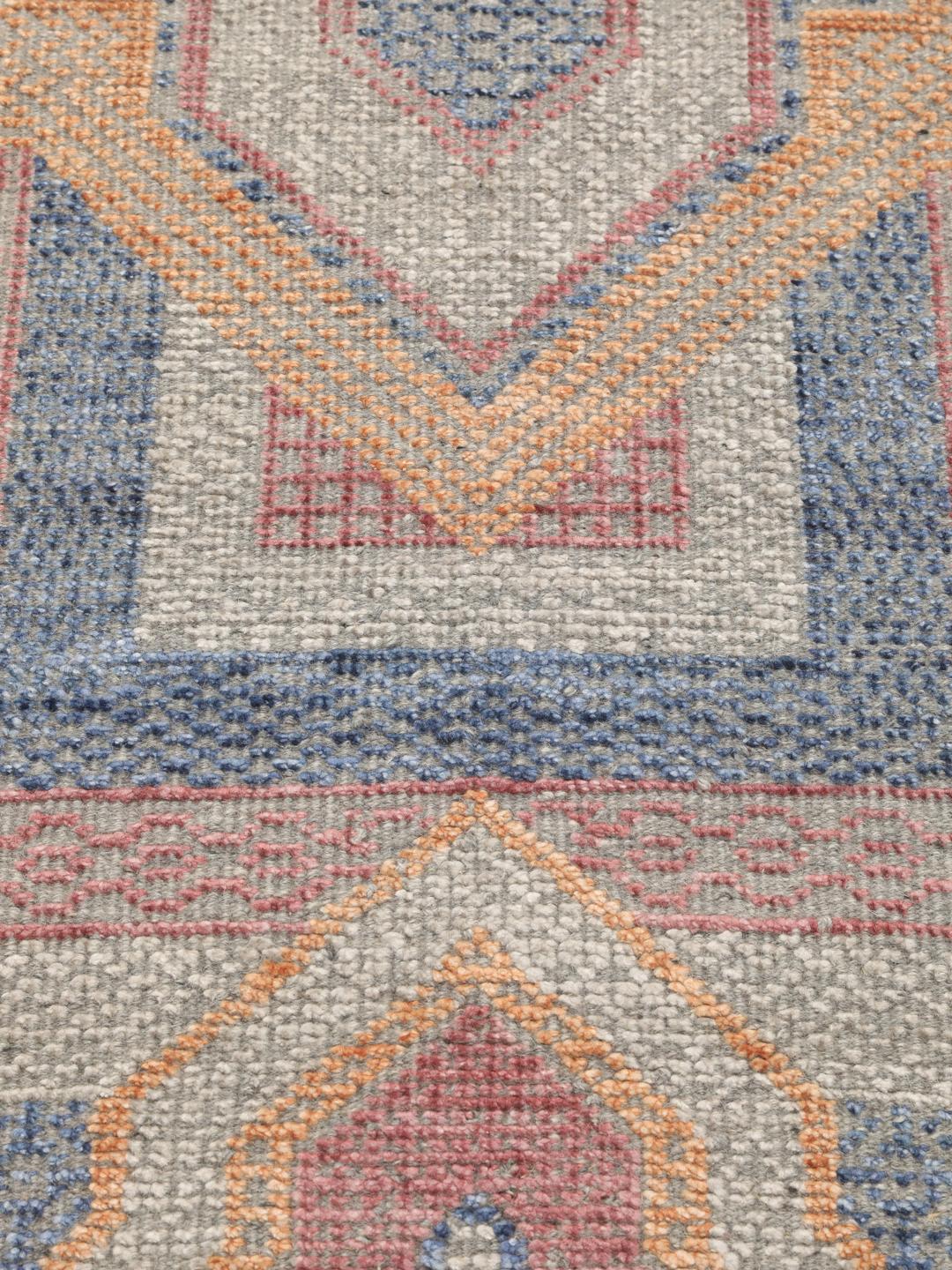 Modern handgeknoopt tapijt uit India met geometrische patronen in blauwe, roze en beige tinten.
