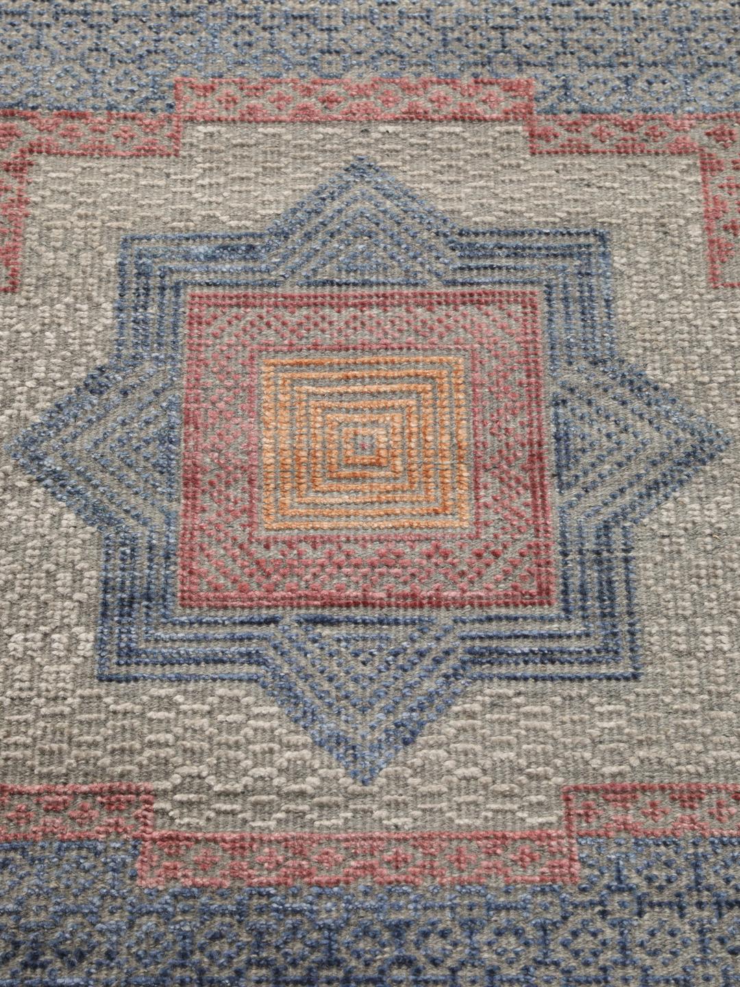 Modern handgeknoopt tapijt uit India met geometrische patronen in blauwe, roze en beige tinten.