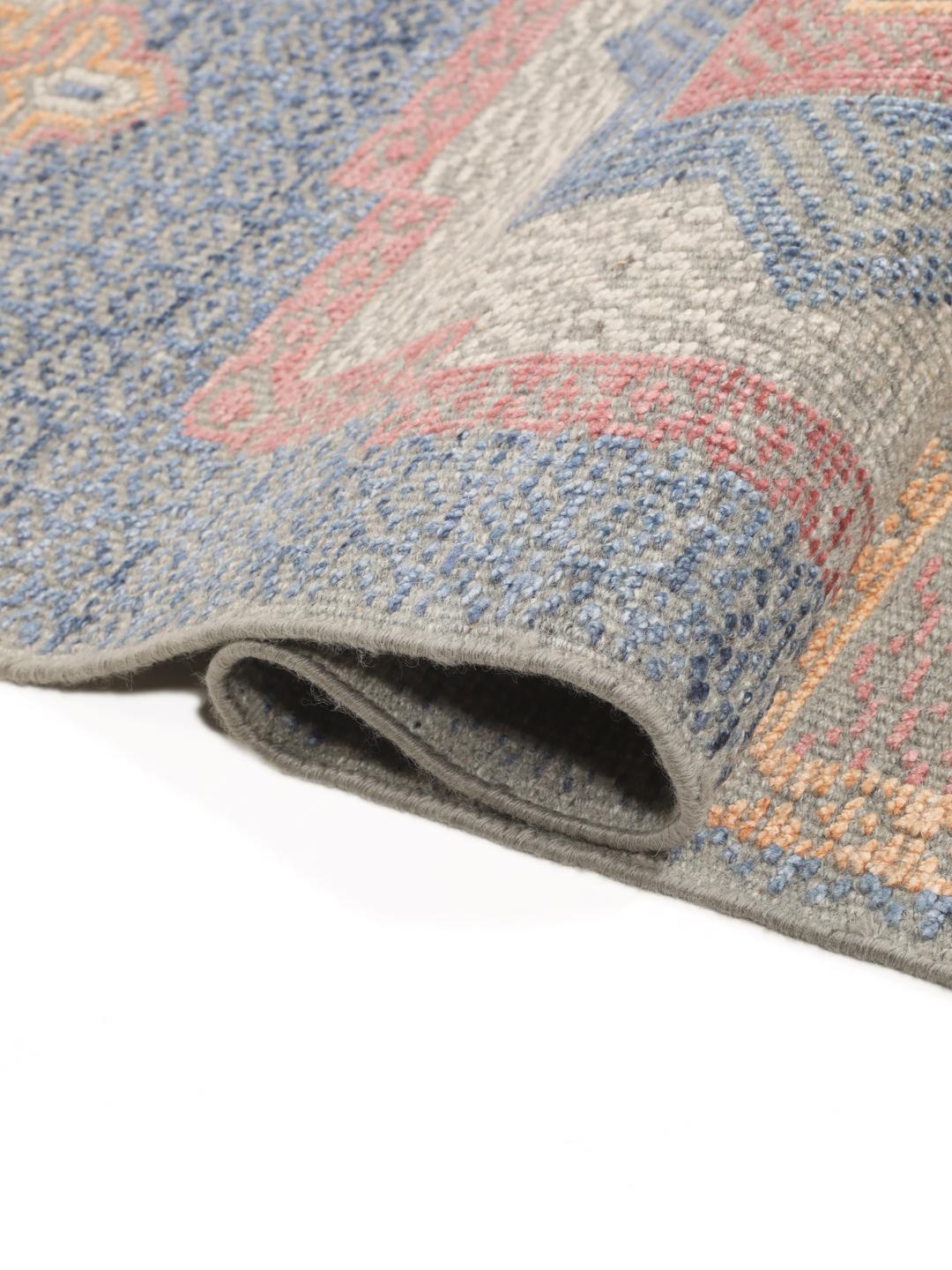 Modern handgeknoopt tapijt uit India met geometrische patronen in blauwe, roze en beige tinten.