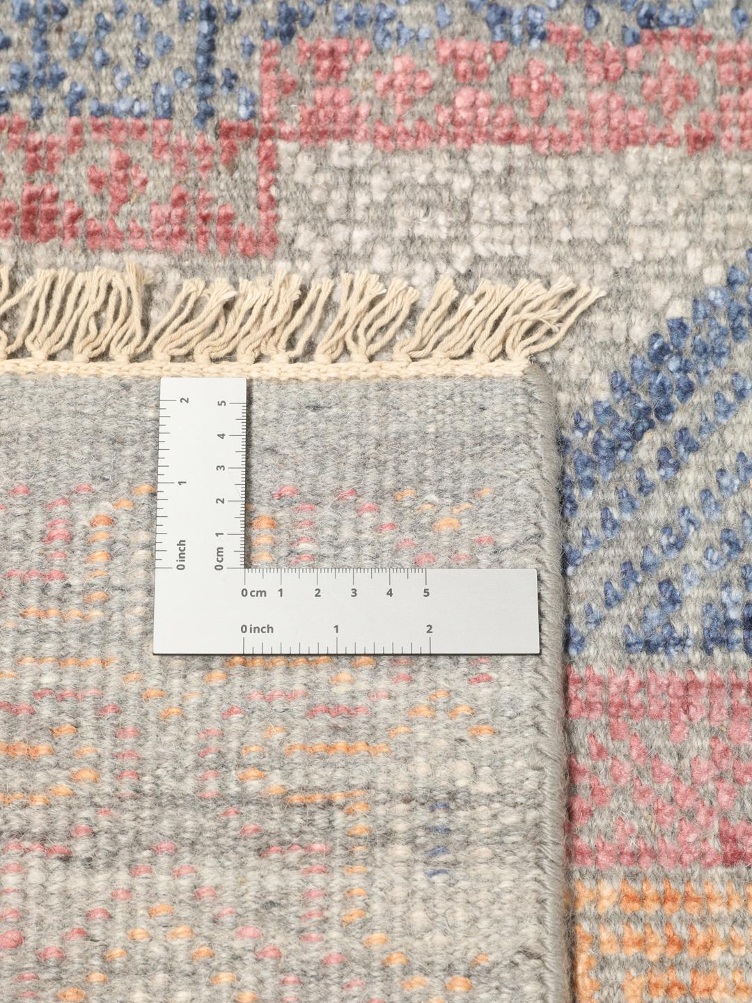 Modern handgeknoopt tapijt uit India met geometrische patronen in blauwe, roze en beige tinten.