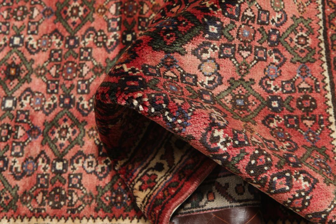 A long, hand-knotted Hosseinabad runner rug with a red field and geometric motifs.