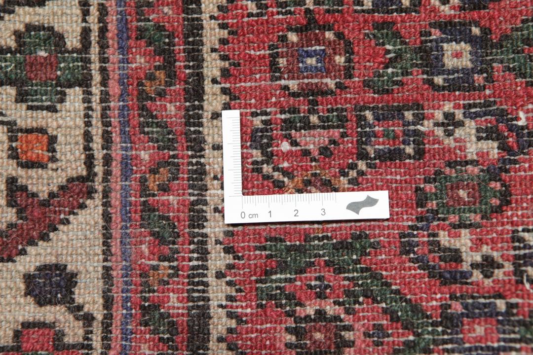 A long, hand-knotted Hosseinabad runner rug with a red field and geometric motifs.