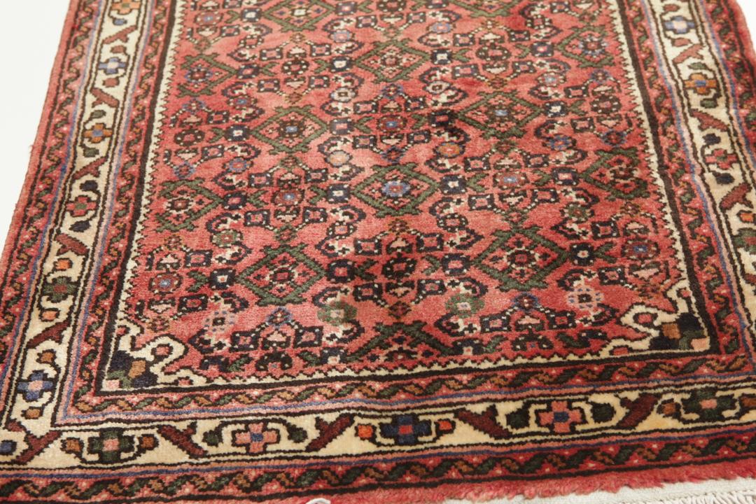 A long, hand-knotted Hosseinabad runner rug with a red field and geometric motifs.