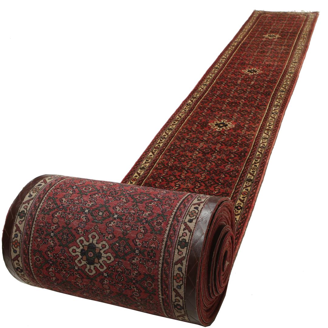 A long, hand-knotted Hosseinabad runner rug with a red field and geometric motifs.