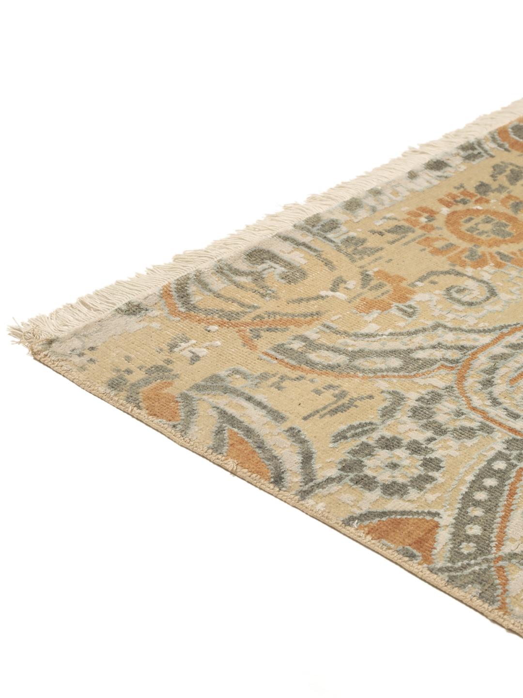Håndknyttet indisk tæppe med et moderne blomstermønster i beige og orange toner.