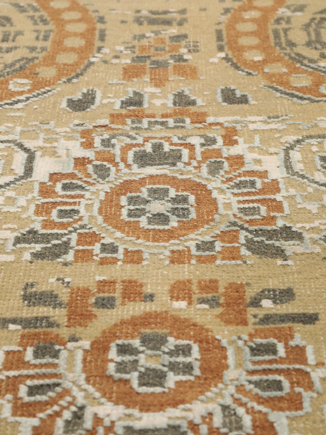 Håndknyttet indisk tæppe med et moderne blomstermønster i beige og orange toner.