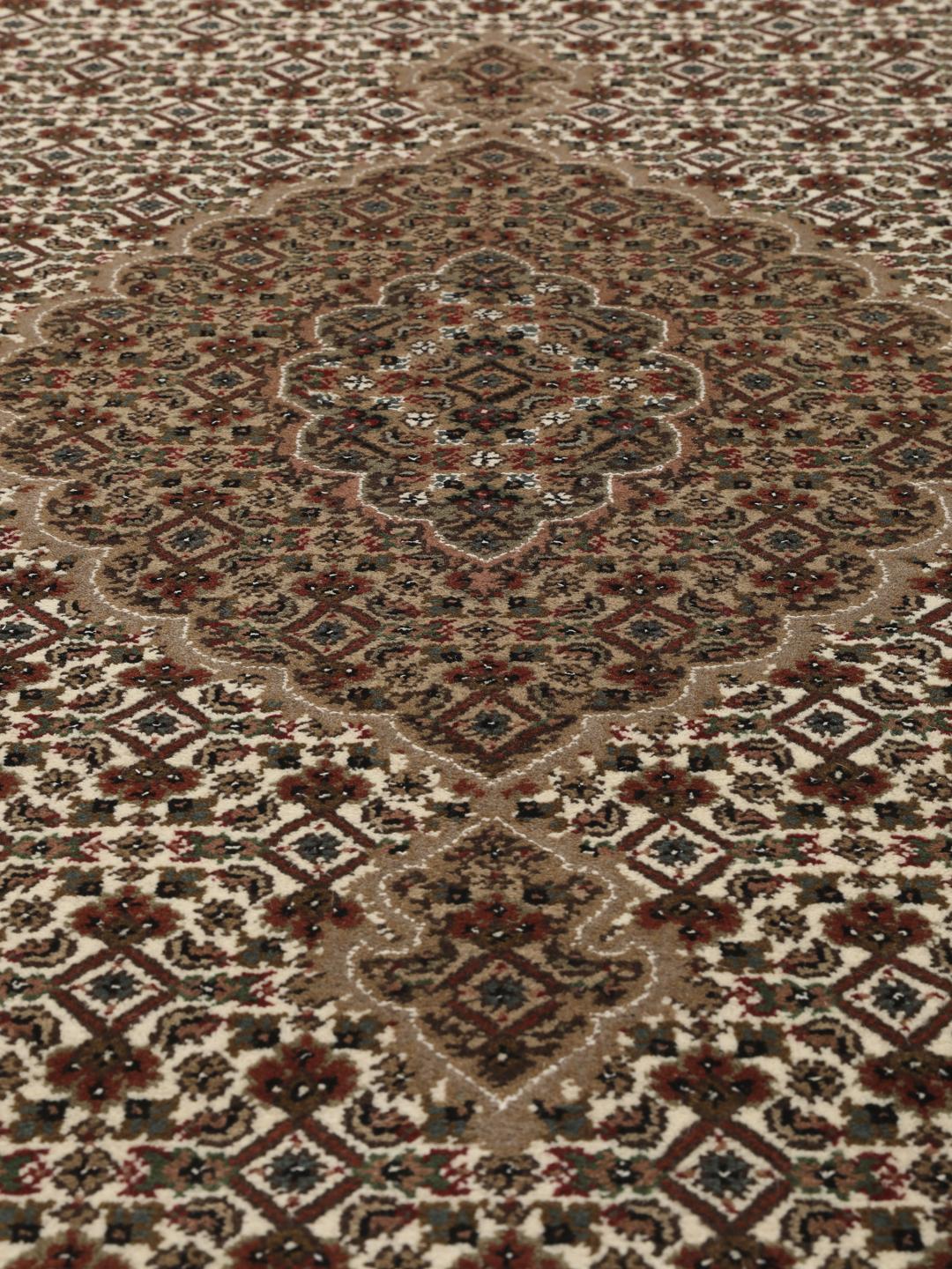 Et rundt, håndknyttet Tabriz-tæppe med detaljeret medaljon og blomstermotiver i brun og creme fra Indien.