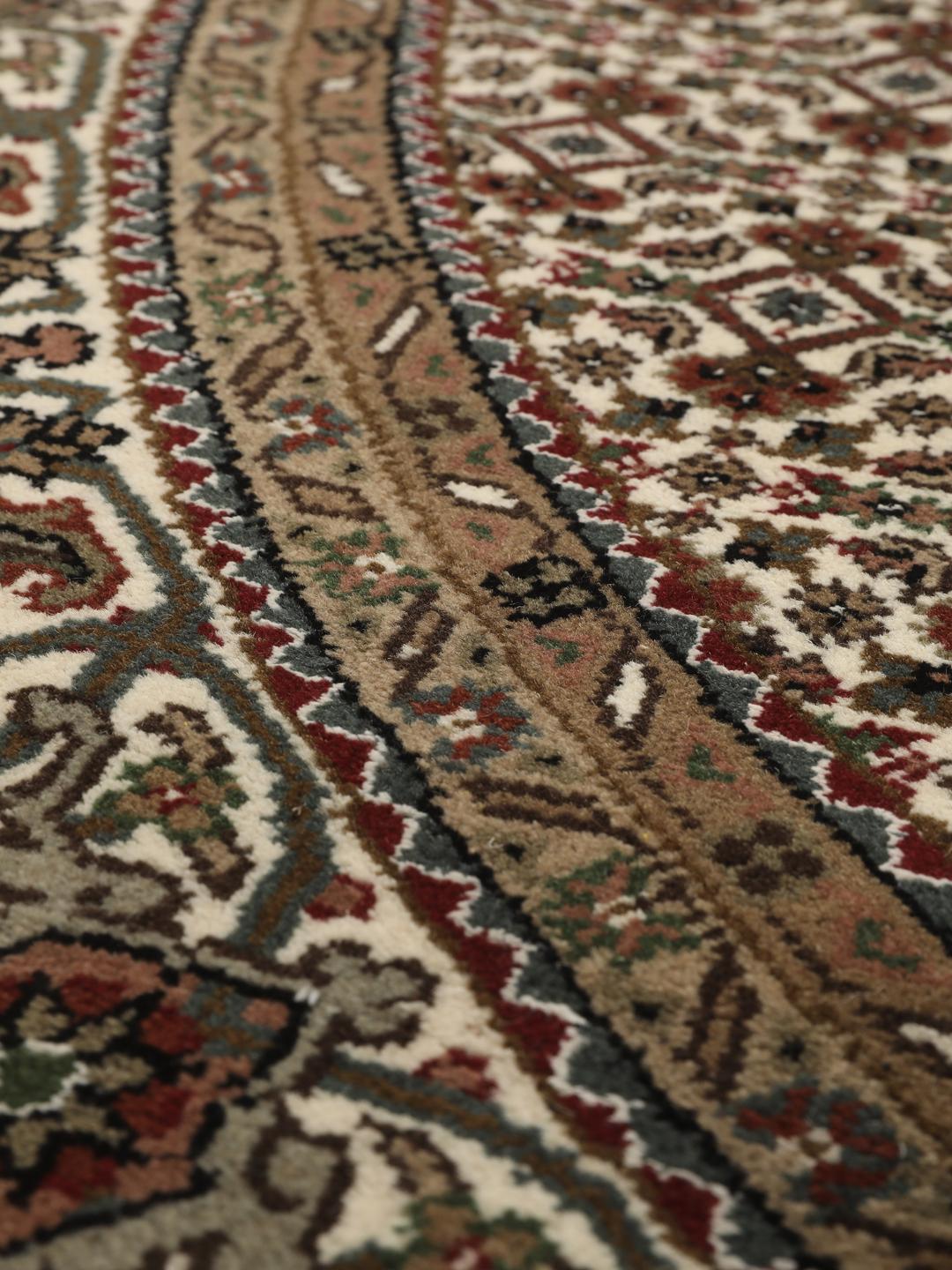 Et rundt, håndknyttet Tabriz-tæppe med detaljeret medaljon og blomstermotiver i brun og creme fra Indien.