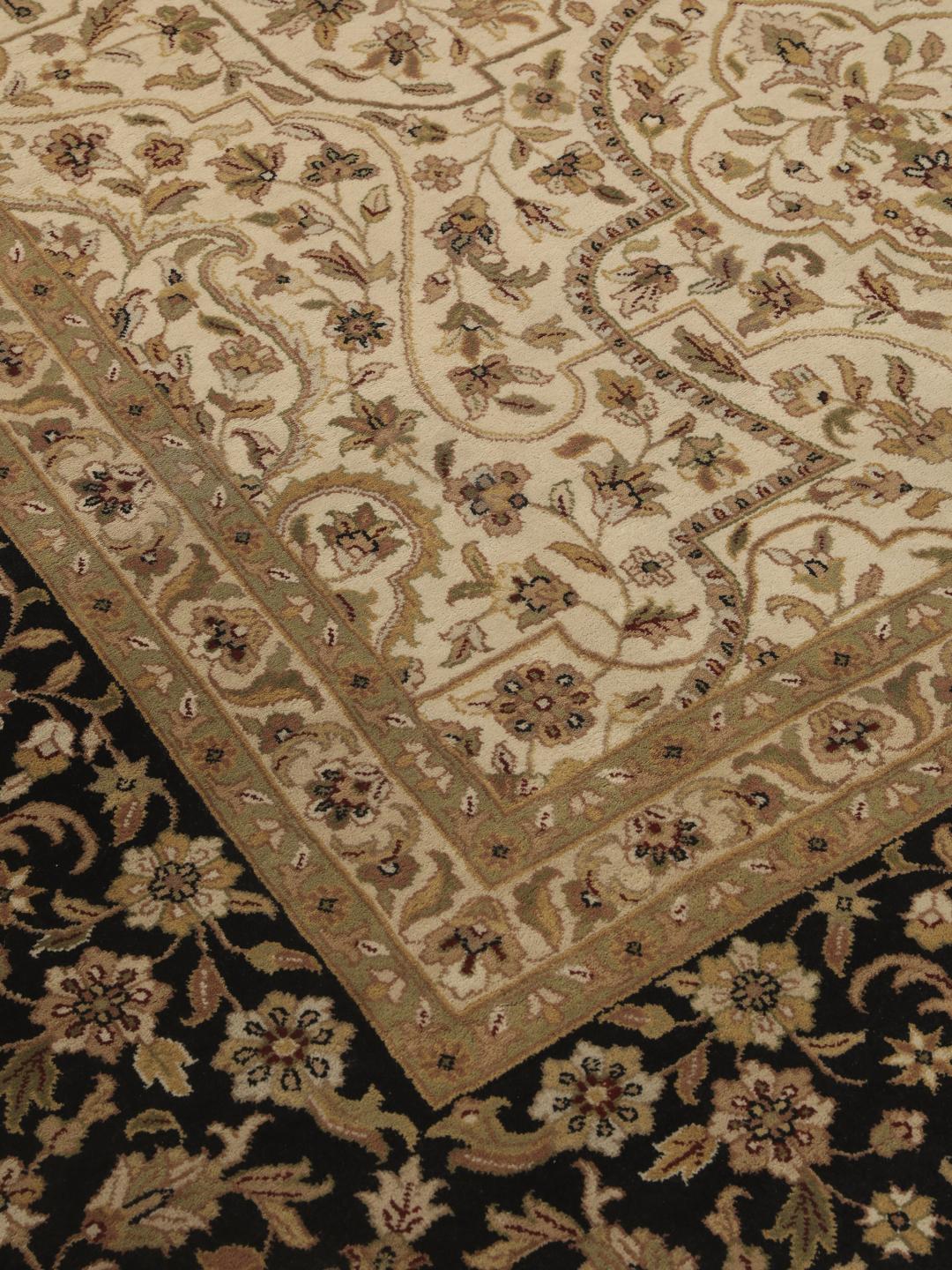 A large, hand-knotted Sarough rug from India featuring an intricate floral design on a beige field with a black border.