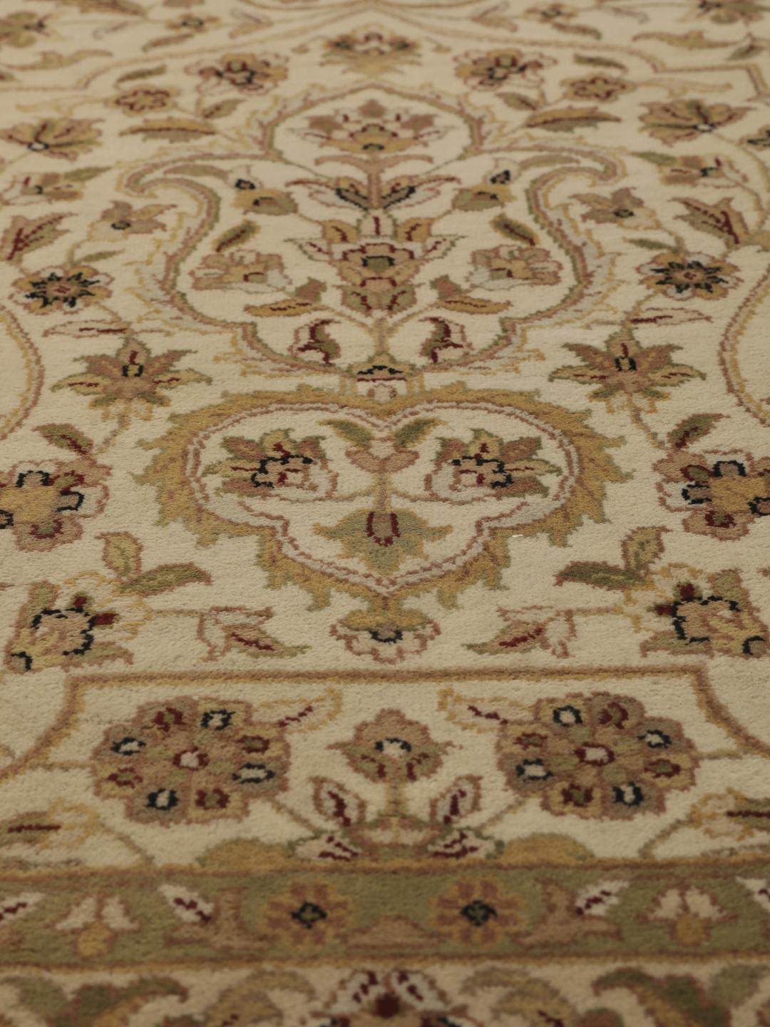 A large, hand-knotted Sarough rug from India featuring an intricate floral design on a beige field with a black border.