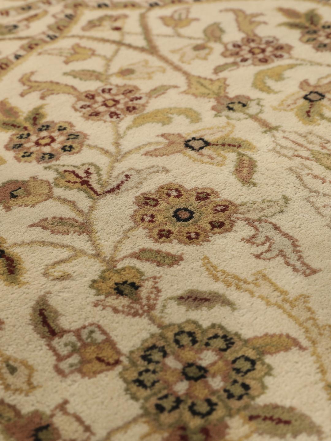 A large, hand-knotted Sarough rug from India featuring an intricate floral design on a beige field with a black border.