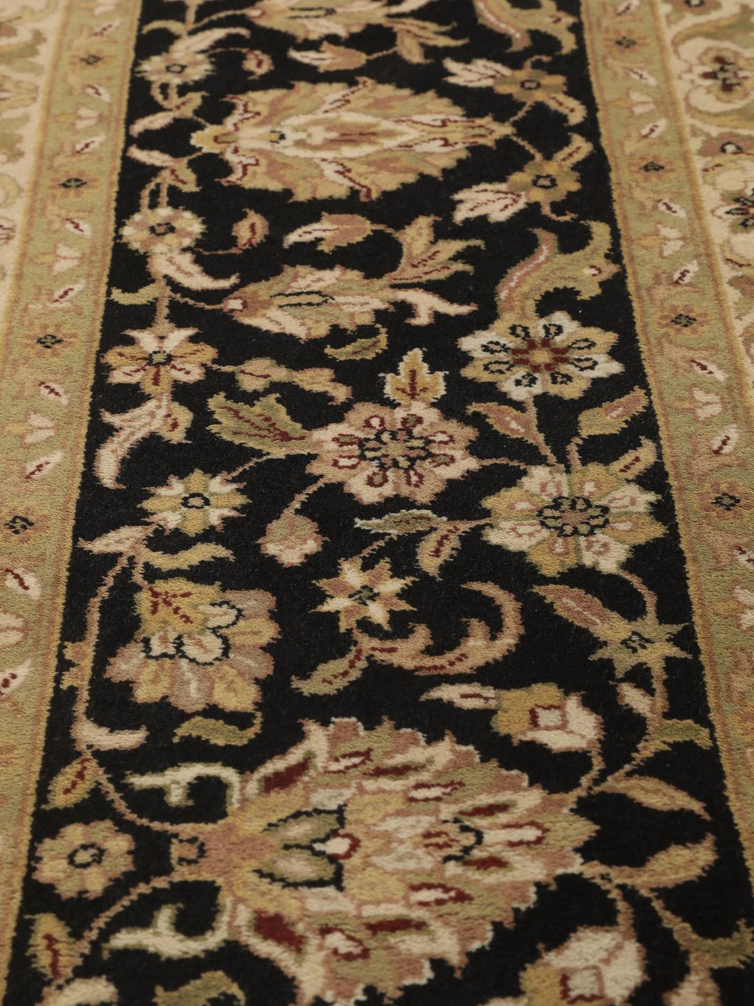 A large, hand-knotted Sarough rug from India featuring an intricate floral design on a beige field with a black border.