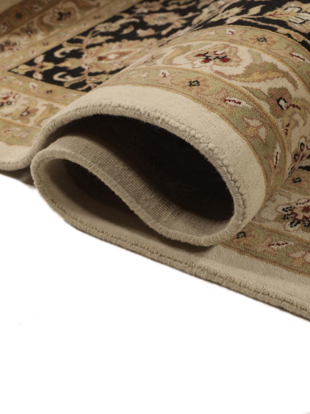 A large, hand-knotted Sarough rug from India featuring an intricate floral design on a beige field with a black border.