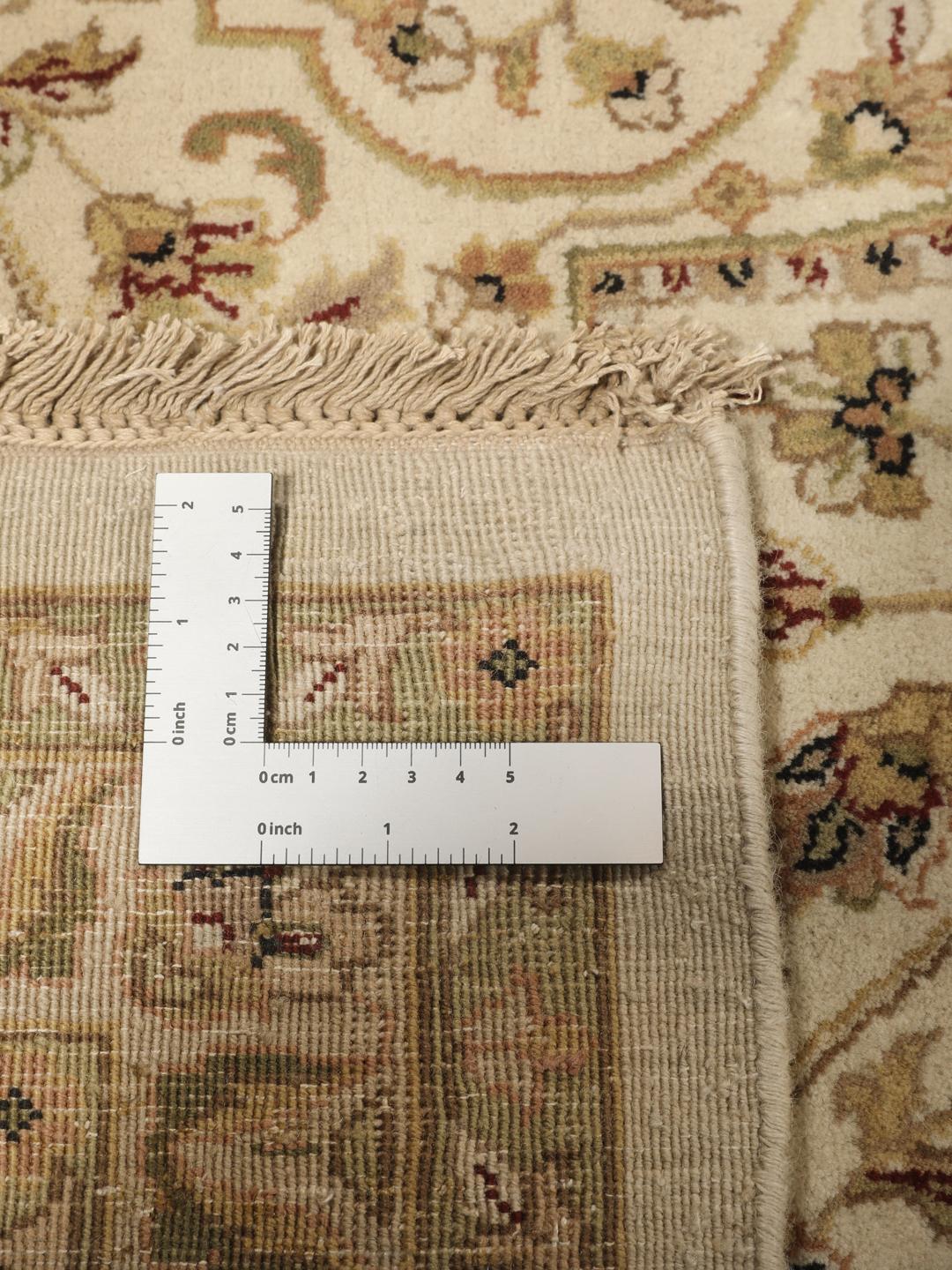 A large, hand-knotted Sarough rug from India featuring an intricate floral design on a beige field with a black border.