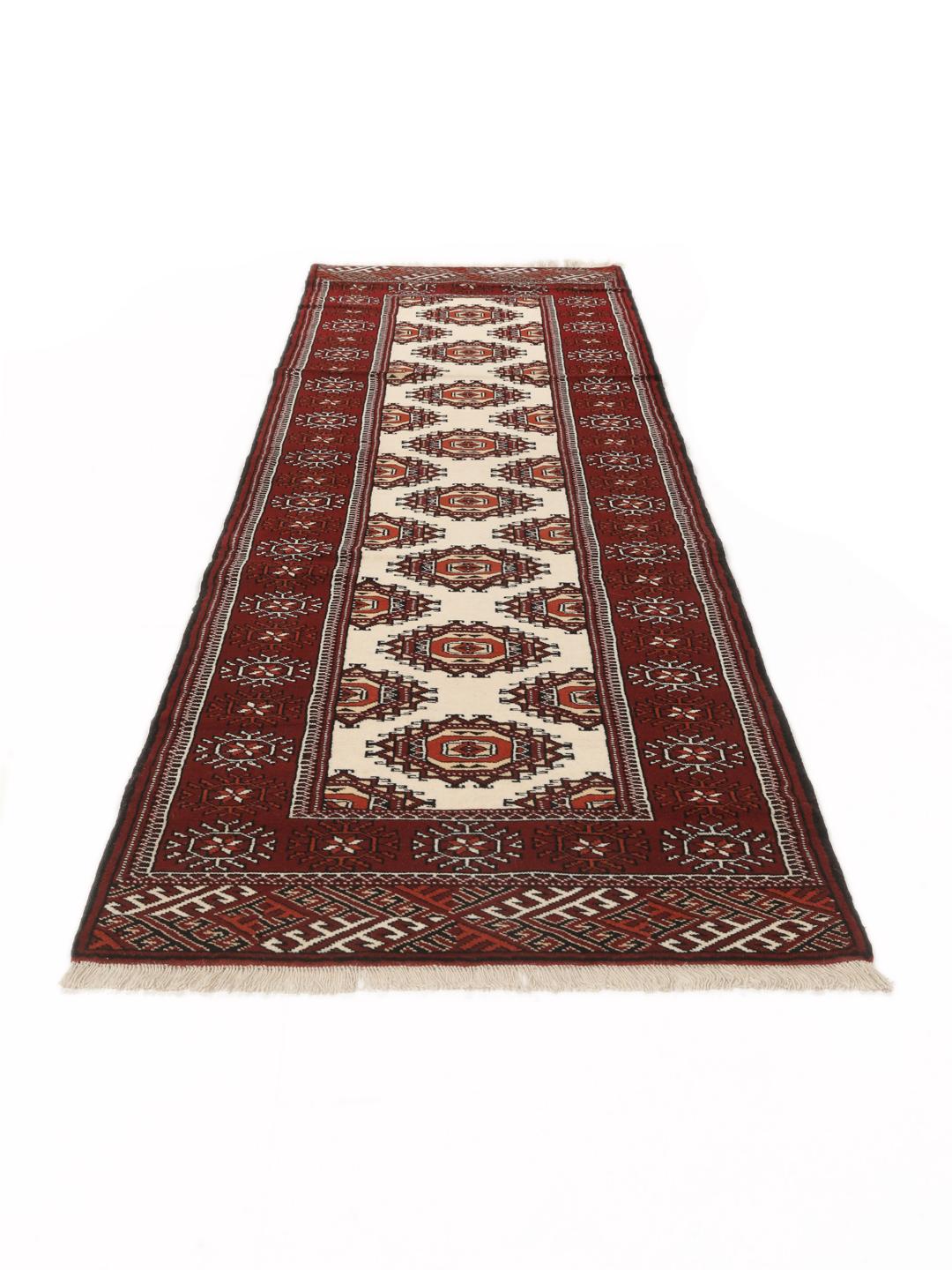 A long, hand-knotted Turkaman runner from the Middle East featuring a vibrant red and cream geometric design.