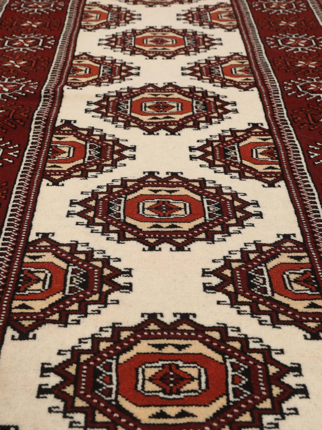 A long, hand-knotted Turkaman runner from the Middle East featuring a vibrant red and cream geometric design.