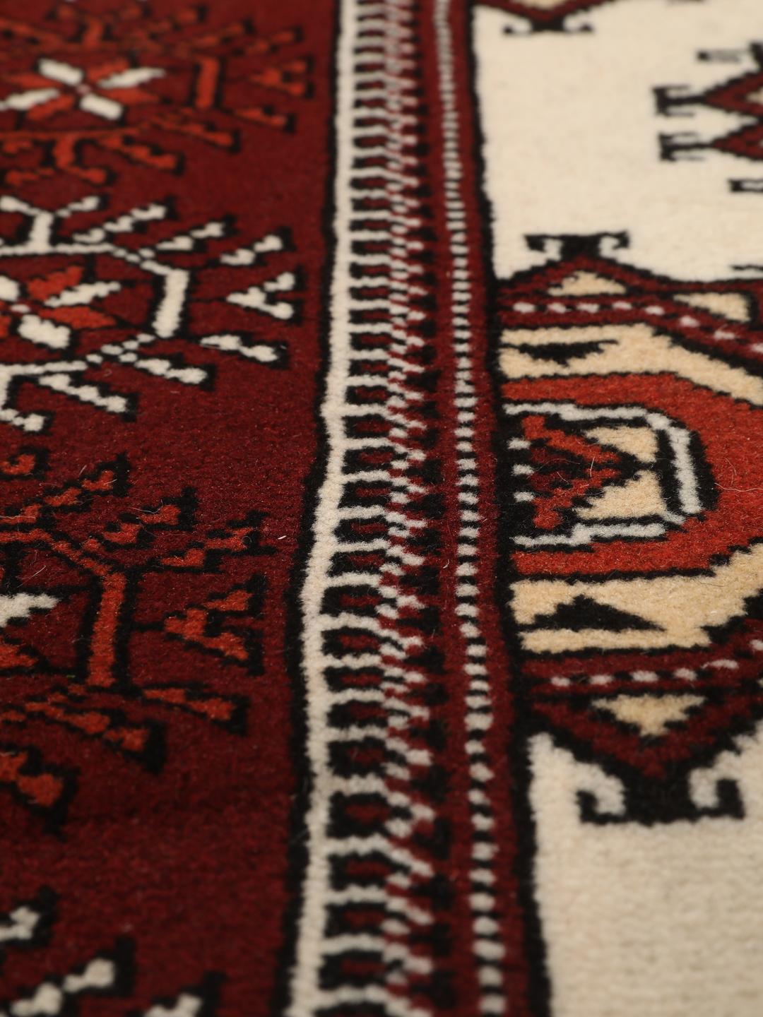 A long, hand-knotted Turkaman runner from the Middle East featuring a vibrant red and cream geometric design.