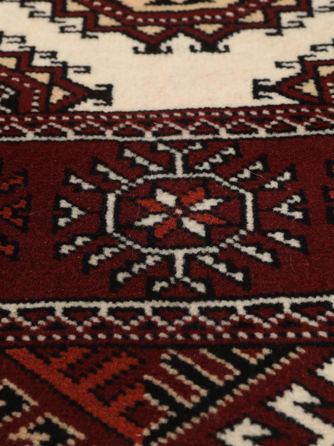 A long, hand-knotted Turkaman runner from the Middle East featuring a vibrant red and cream geometric design.