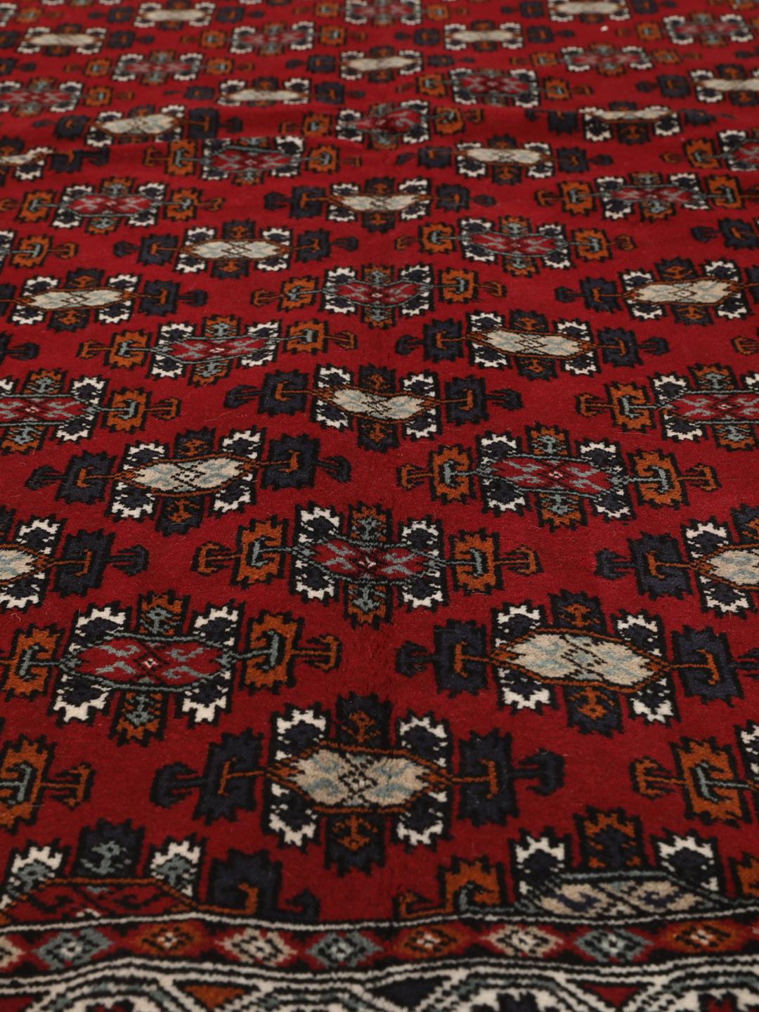 Hand-knotted Turkaman wool rug with a vibrant red field and tribal geometric patterns from the Middle East