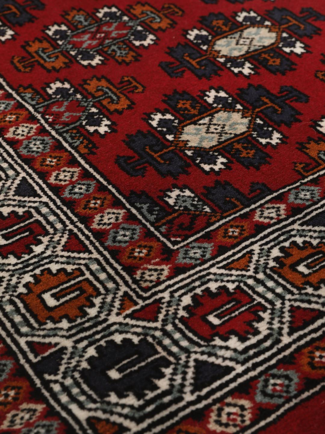 Hand-knotted Turkaman wool rug with a vibrant red field and tribal geometric patterns from the Middle East