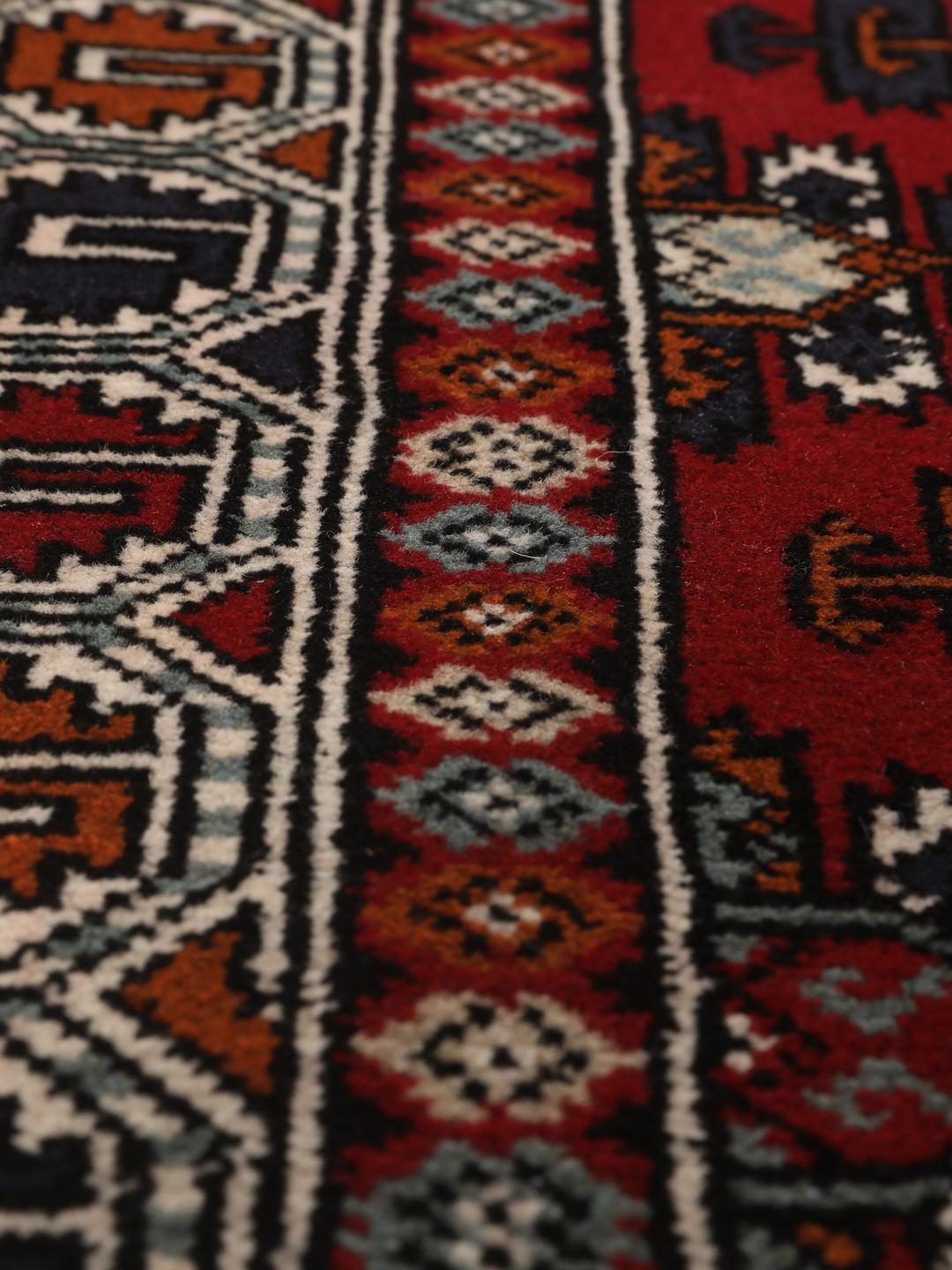 Hand-knotted Turkaman wool rug with a vibrant red field and tribal geometric patterns from the Middle East