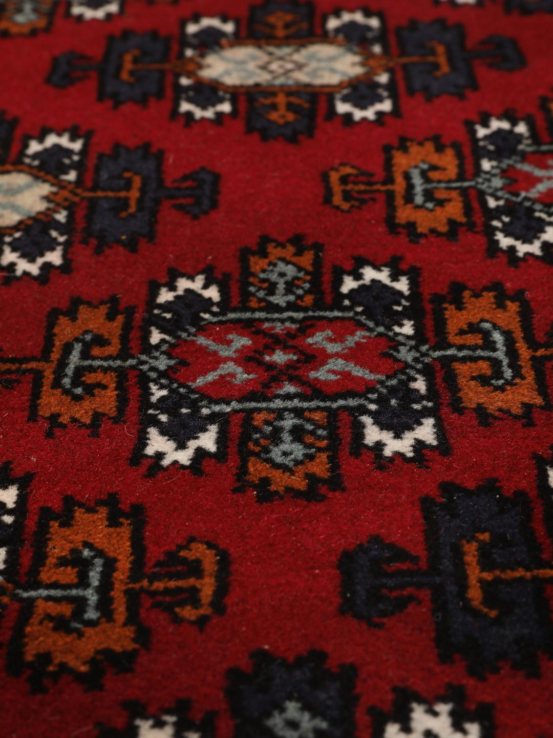 Hand-knotted Turkaman wool rug with a vibrant red field and tribal geometric patterns from the Middle East