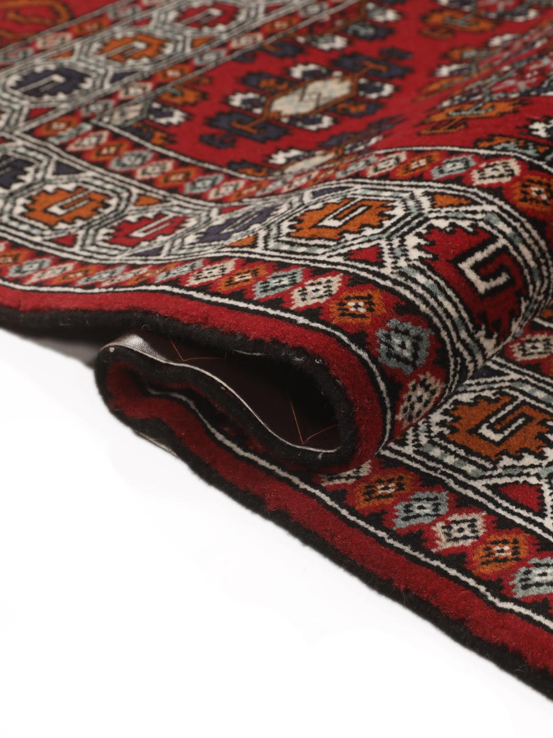 Hand-knotted Turkaman wool rug with a vibrant red field and tribal geometric patterns from the Middle East
