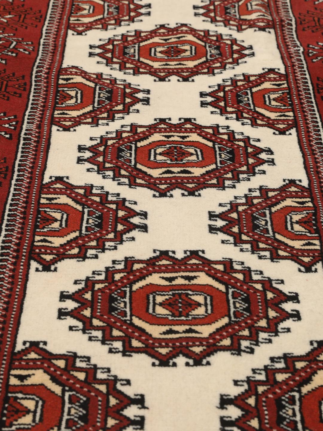 A hand-knotted red Turkaman runner with intricate geometric patterns.