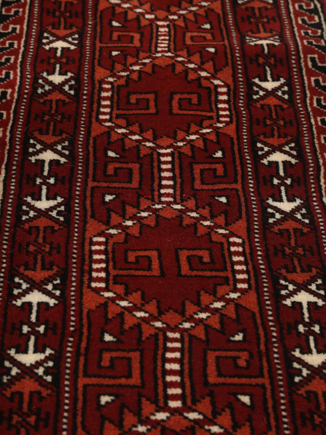 Hand-knotted Turkaman rug with a deep red field and geometric motifs